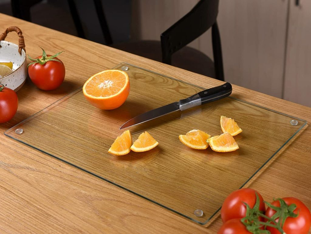 knife and oranges on glass cutting board