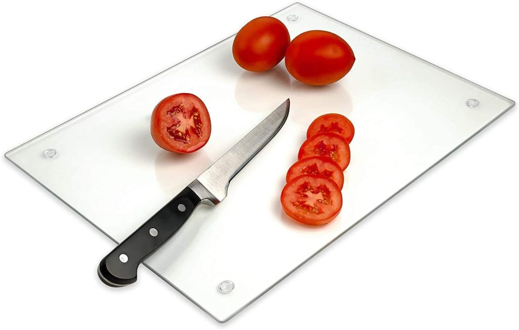 knife and sliced tomatoes on glass cutting board