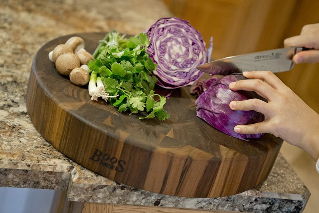person slicing cabbage on round wooden cutting board