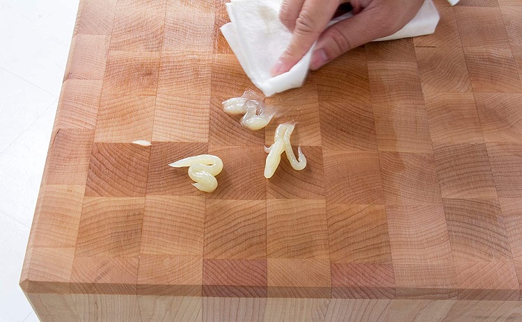person using paper towel to rub conditioner into cutting board