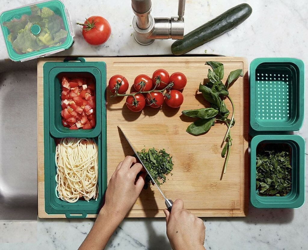 persons hands chopping vegetables on cutting board with teal containers
