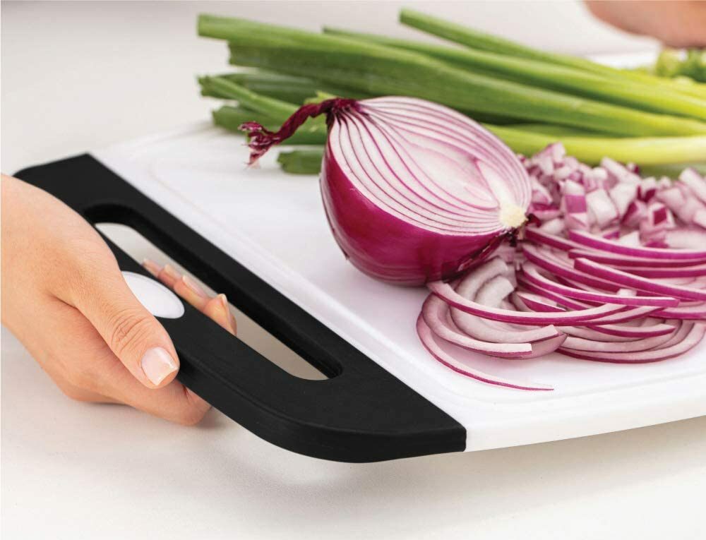 raw red onion and vegetables on plastic cutting board with black handle