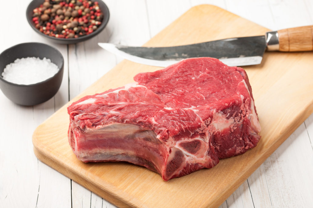 Raw beef meat with bone on cutting board