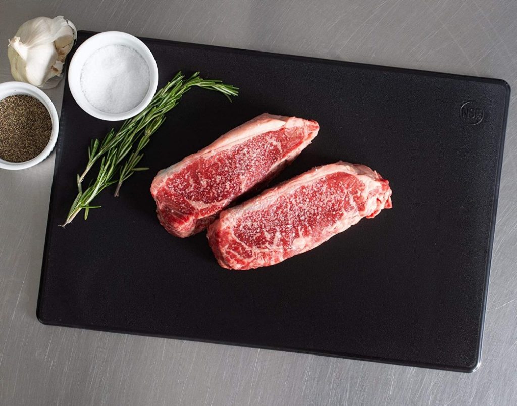 raw steaks and seasonings on black cutting board