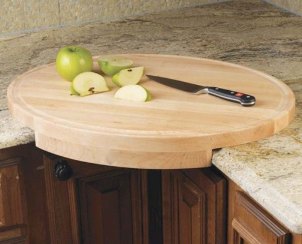 round cutting board in corner of counter with apples being sliced
