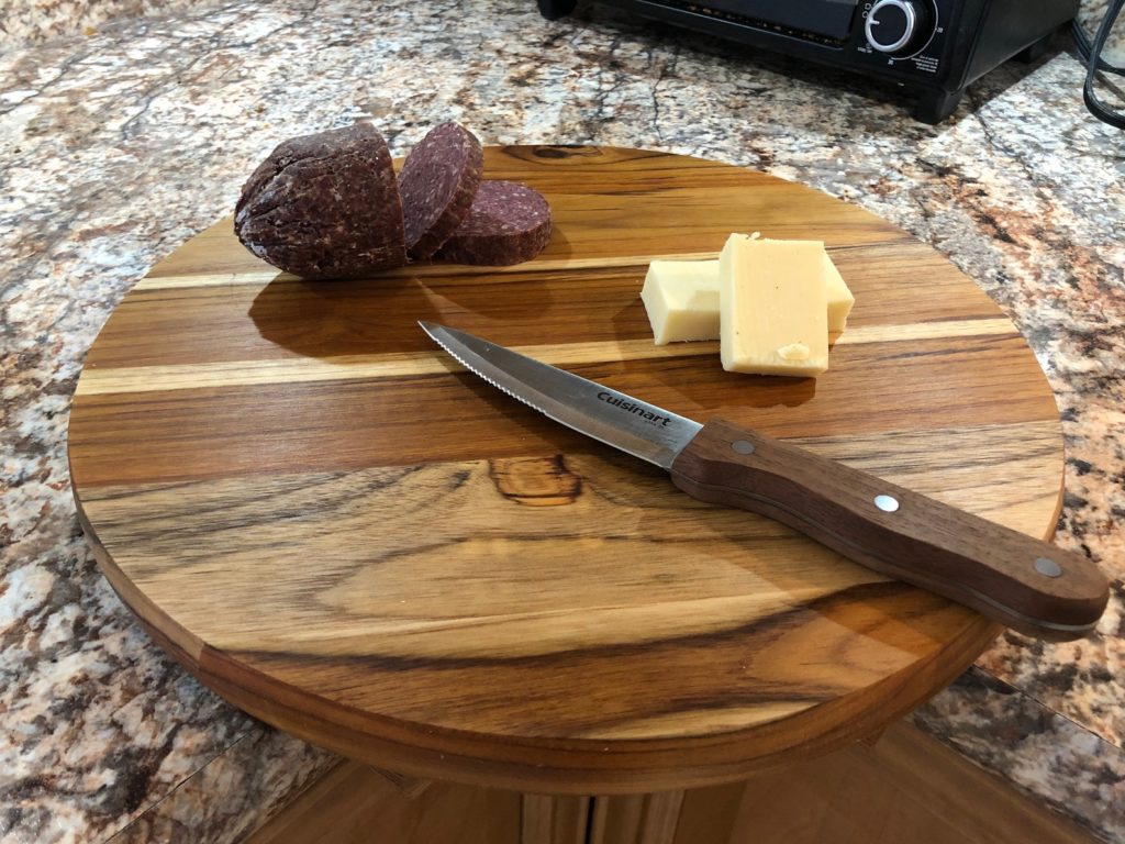 round wooden corner cutting board with fruit and cheese