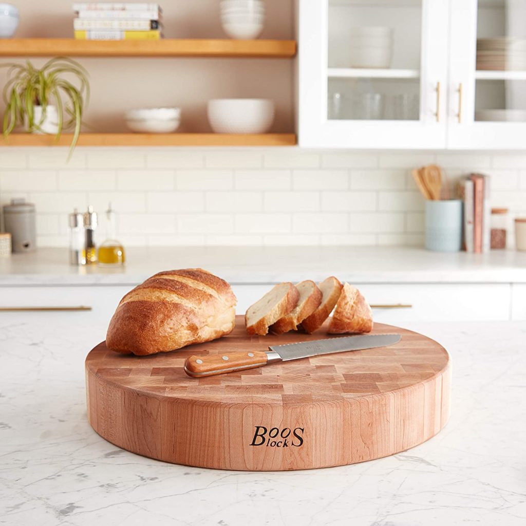 sliced bread and knife on round butcher block cutting board in kitchen