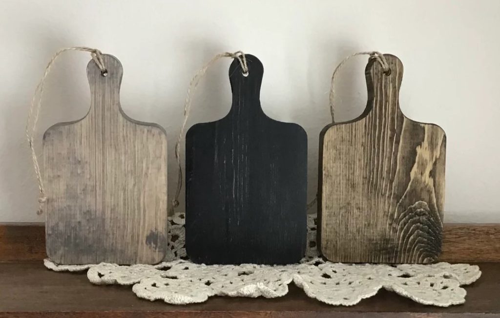 three wooden and black farmhouse cutting boards with handles
