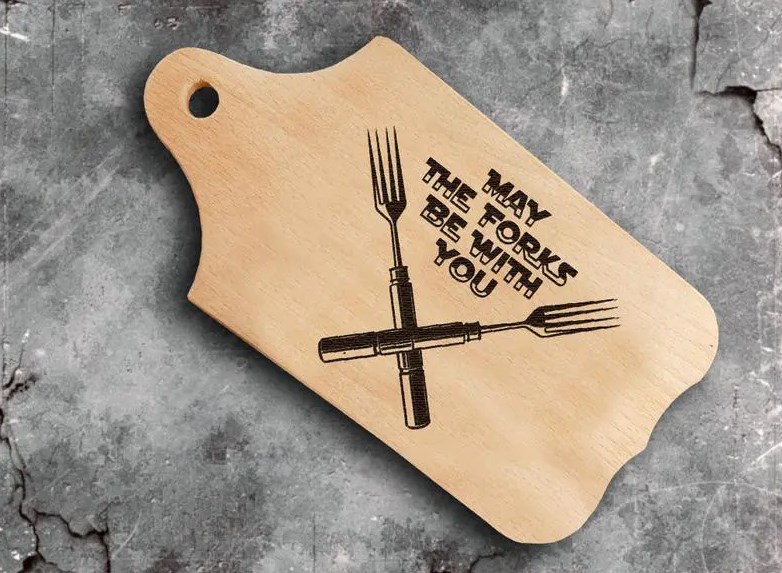 two crossed forks and MAY THE FORKS BE WITH YOU burnt into wooden cutting board