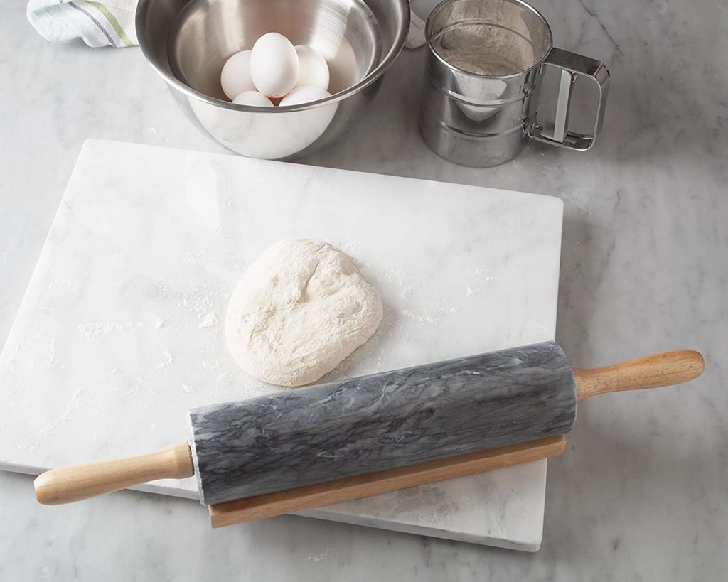 dough on white marble cutting board with grey marble rolling pin