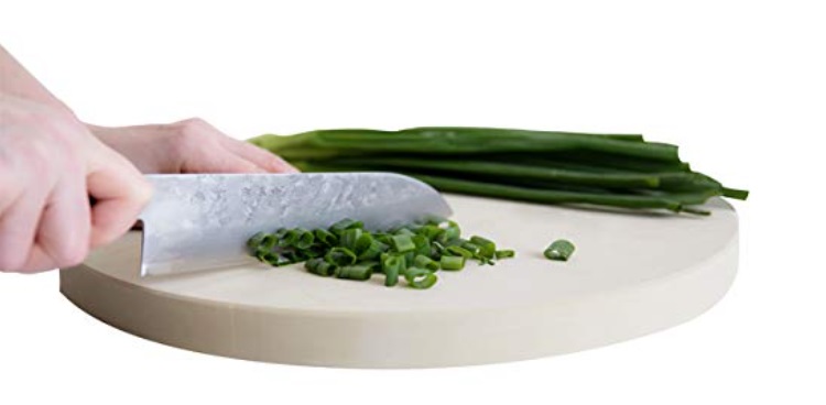 womans hand slicing scallions on cutting board